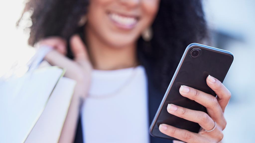 Woman's face and hand with cell phone, shopping bags